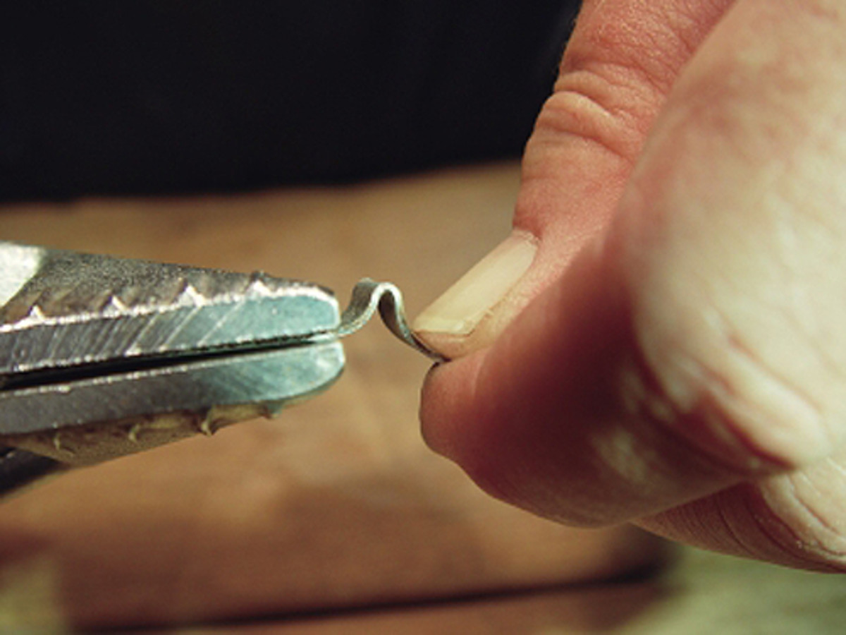  The metal strip is now gripped in the pliers as close to the bend as possible, and an attempt is made to bend it back straight by hand.