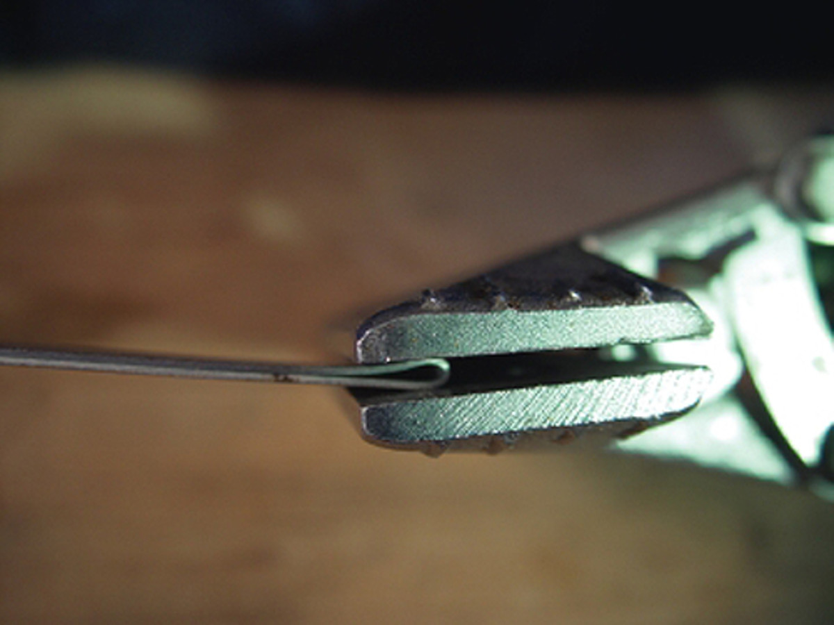  Now the metal is gripped between the pliers' jaws and compressed slightly.